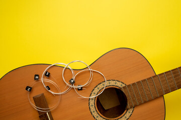 new strings, prepared for installation on the guitar, lie on the guitar deck. yellow background and space for text
