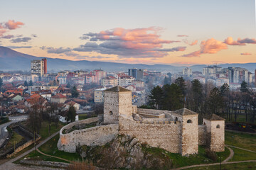 Beautiful soft colors of the clouds on a sunset sky above ancient fortress in front of a scenic, misty, dreamy cityscape of Pirot, Serbia