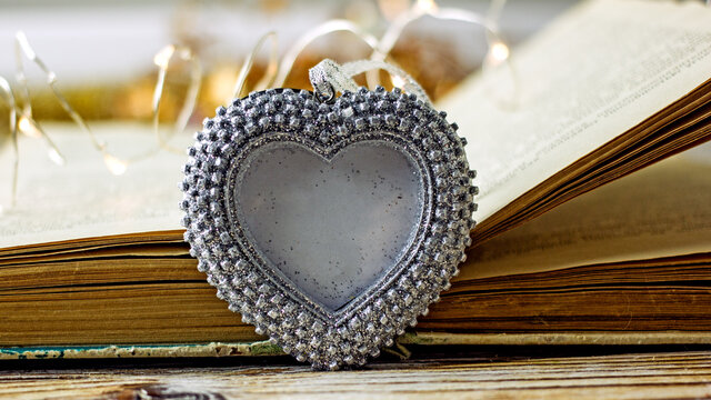 Heart  background. A decorative silvery heart frame with a place for text on a wooden light table. Concept background for valentine's day, wedding, romantic invitation. Copy space
