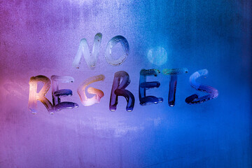 words no regrets hand written on purple-blue night foggy window glass
