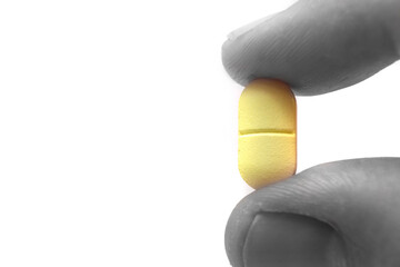 yellow and notched pill held between two fingers