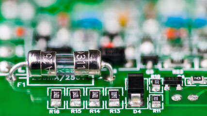 Electrical glass fuse or resistors, diode and transistor on printed circuit board in artistic...