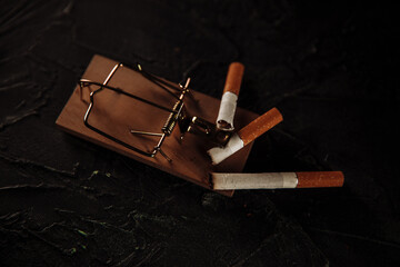 Three cigarettes on a mouse trap. Top view. Toxic addiction concept.