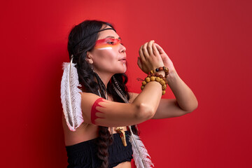 female with art native american creative warrior combat makeup in studio, making rituals. indian...