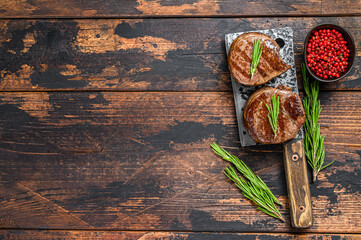 Grilled fillet mignon steak on a meat cleaver. Dark wooden background. Top view. Copy space