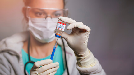 Doctor holding a syringe with a single bottle vial of Covid-19 vaccine and she is ready for...