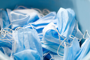 Many stacked medical blue masks. A lot of used crumpled protective medical masks on a blue background. Coronavirus, covid-19, pandemic, epidemic. Selective focus