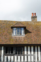 The exterior of a typical Tudor house in Rye, England including a white facade with wood trim, a window, and a sloped roof.  Image has copy space.