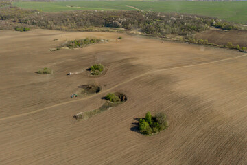 Aerial view large tractor cultivating a dry field. Top down aerial view tractor cultivating ground...