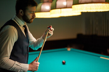 man preparing to play professional billiards in the dark billiard club, spend pleasant time - obrazy, fototapety, plakaty