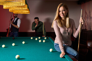 young active friends are playing billiards in bar after work, have rest and leaisure time,...