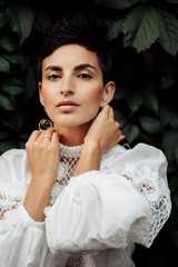 Portrait of gorgeous pretty woman outdoor, looking at the camera. Adorable stylish lady in luxury formal clothing and jewelry, posing with fashion natural makeup. Female beauty concept