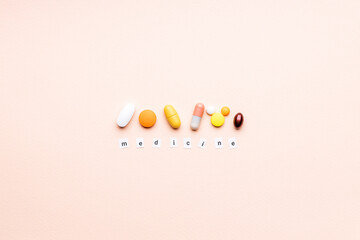 words medicine near assorted pills over pink background. creative medicine and drug concept....