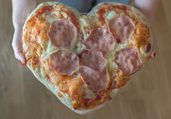 Valentines day heart shaped pizza held by a woman. 