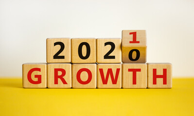 2021 growth symbol. Turned a wooden cube, changed words 'growth 2020' to 'growth 2021'. Beautiful yellow table, white background, copy space. Business, 2021 growth new year concept.