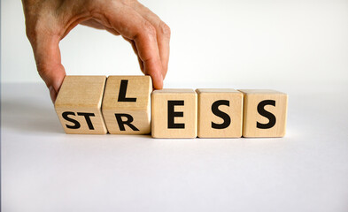Having less stress or being stress-less. The word 'STRESS' and 'LESS' on wooden cubes. Male hand....