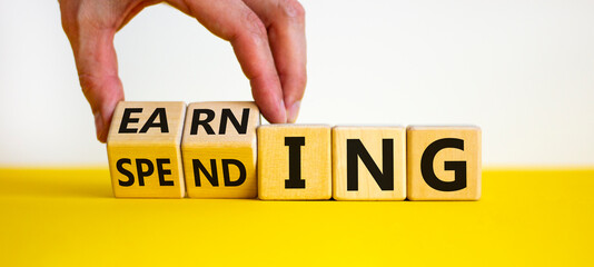 Earning or spending symbol. Businessman hand turns cubes and changes the word 'spending' to 'earning'. Beautiful white background, copy space. Business and earning or spending concept.