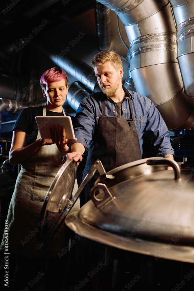 Sticker young woman with tablet showing list of beer processing stages to male colleague