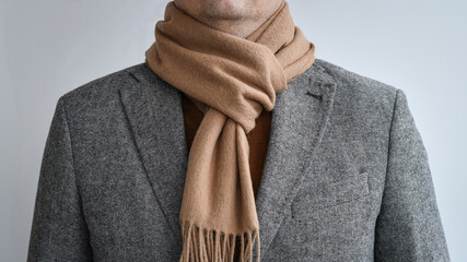 Detail of mens outfit, fashionable grey tweed blazer combined with light beige scarf.  Selective focus.