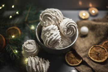 Homemade marshmallows on a background of candles, oranges and fir branches. Christmas still life