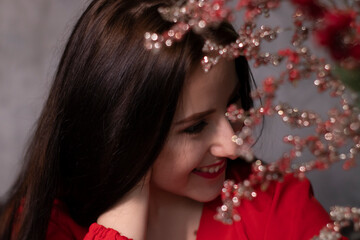 Naklejka premium portrait of attractive brunette woman in red blouse near decorative sparkling red branches boquet. st valentines