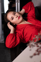 portrait of attractive brunette woman in red blouse lying on leather couch. st valentines.