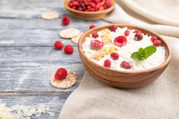 Rice flakes porridge with milk and strawberry in wooden bowl on gray wooden background. Side view, selective focus.