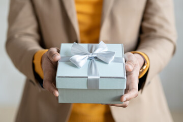 Hands of young elegant businessman passing you packed gift in light blue giftbox