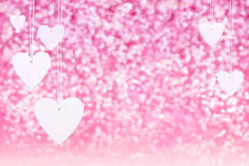 Hangning white decorative hearts on bright glossy pink background