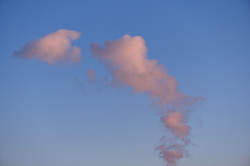 Rosa leuchtende Wolken / Dampf vor blauem Himmel