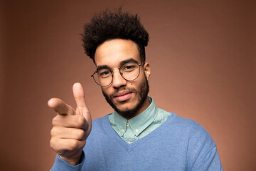 Young contemporary mixed-race businessman in eyeglasses pointing at you