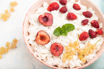 Rice flakes porridge with milk and strawberry in ceramic bowl on white concrete background. Top view, close up.