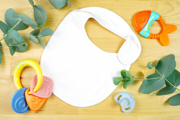 Light natural theme baby apparel top view flat lay with white bodysuit, bib, letter board notice board, for clothing mockups and pregnancy and birth announcements. Mock up