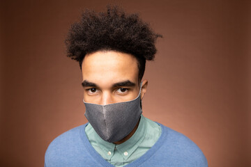 Young serious mixed-race businessman in casualwear and grey protective mask