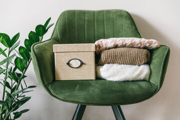 Stack of clothes on a green chair in a light room. Home space organization, spring cleaning and...