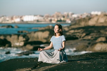 Yoga woman meditates in the lotus position on the ocean coast.