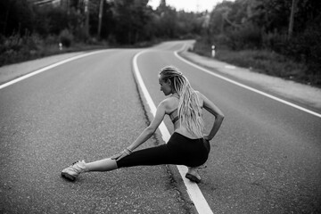 Woman warm-up before jogging on the road. Black and white photo.