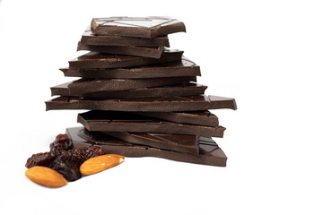 Closeup pieces of dark, inferior chocolate, almonds and raisins on a white background