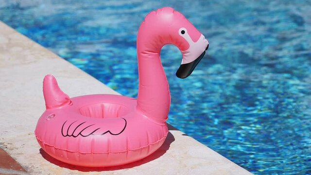 Inflatable toy of pink flamingo near swimming pool at poolside, nobody