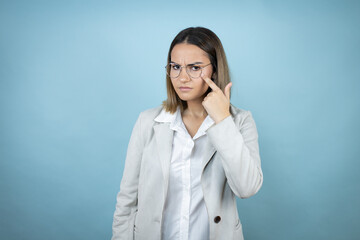 Young business woman over isolated blue background Pointing to the eye watching you gesture, suspicious expression