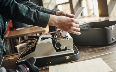 a business man hand pulling a sheet of paper from an old grungy manual portable typewriter