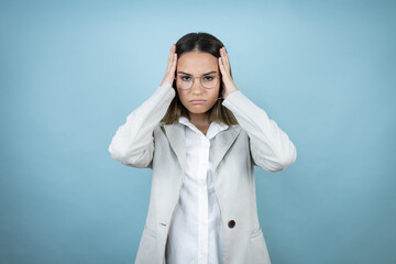 Young business woman over isolated blue background thinking looking tired and bored with hands on head