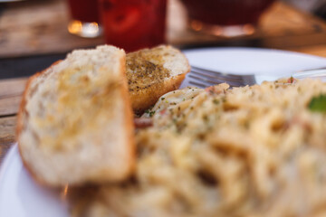 Plato de pasta carbonara con pan al ajo
