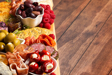 A Savoury Charcuterie Board Covered in Meats Olives Peppers Berries and Cheese