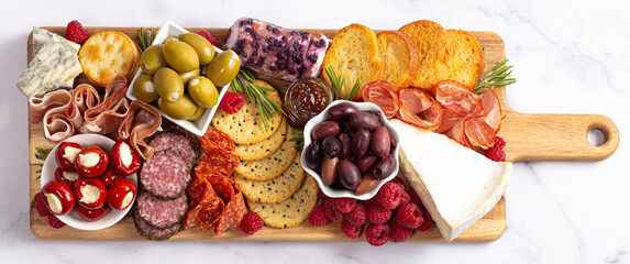A Savoury Charcuterie Board Covered in Meats Olives Peppers Berries and Cheese - Powered by Adobe