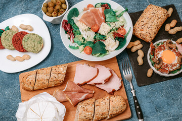 Meat platter and Camembert cheese with baguette. Salad with prosciutto. Olives. Perfect fried eggs with mushrooms and spices. Vegan vegetable cutlets and peanuts. 