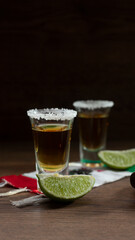 shots of Mexican tequila with salt on the rim and lemons, on a scarf of the Mexican flag with the phrase viva mexico