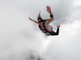 Young woman parachutist in the clouds free fall. Perfect concept of happiness and freedom.