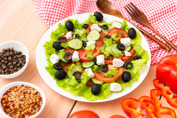 On the table is a plate of freshly prepared Greek salad and feta cheese.