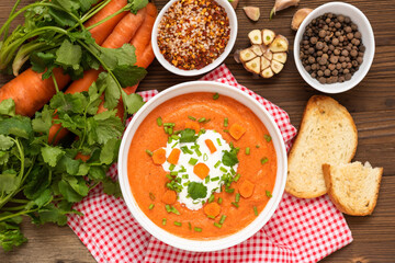 Delicious traditional carrot soup with herbs and sour cream.  Top view.